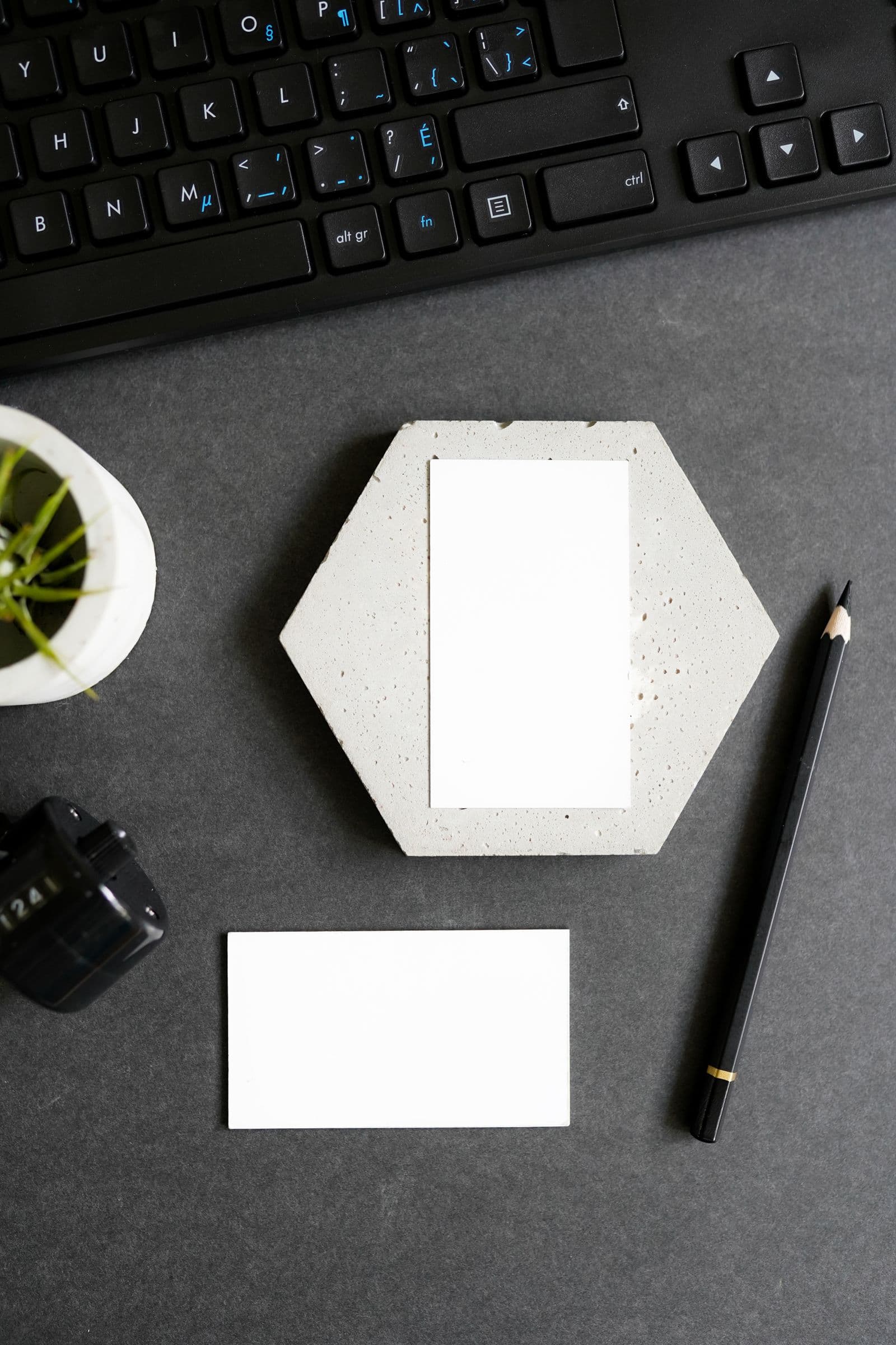 Blank business cards and a gold-banded pencil on a dark desk